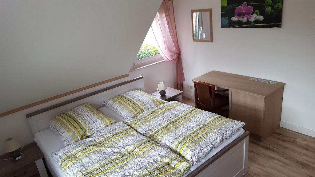1 dormitorio con cama, escritorio y ventana en Gästehaus Strudthoff, en Ganderkesee