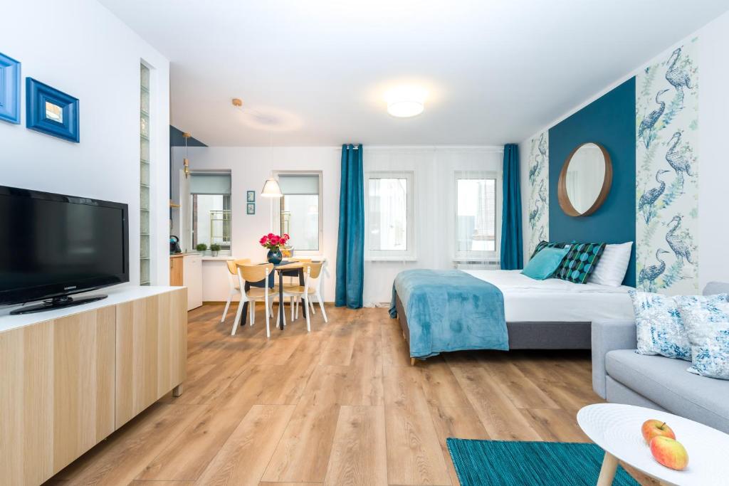 Habitación con cama, TV y sofá. en Sleepway Apartments - Blue Dream, en Poznan