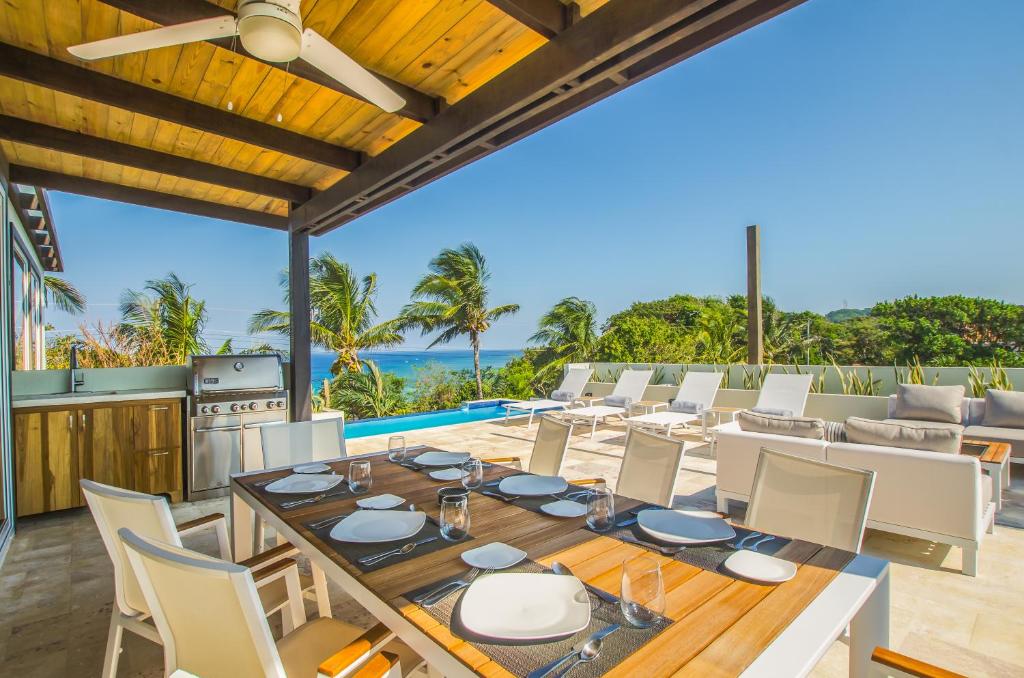 an outdoor dining room with a table and chairs at Villa Topaz Above West Bay with 360 Degree Views! in West Bay