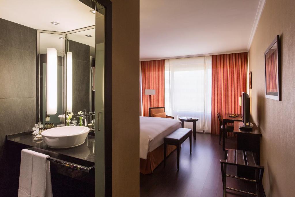 Habitación de hotel con cama, lavabo y espejo en Pullman Madrid Airport & Feria, en Madrid
