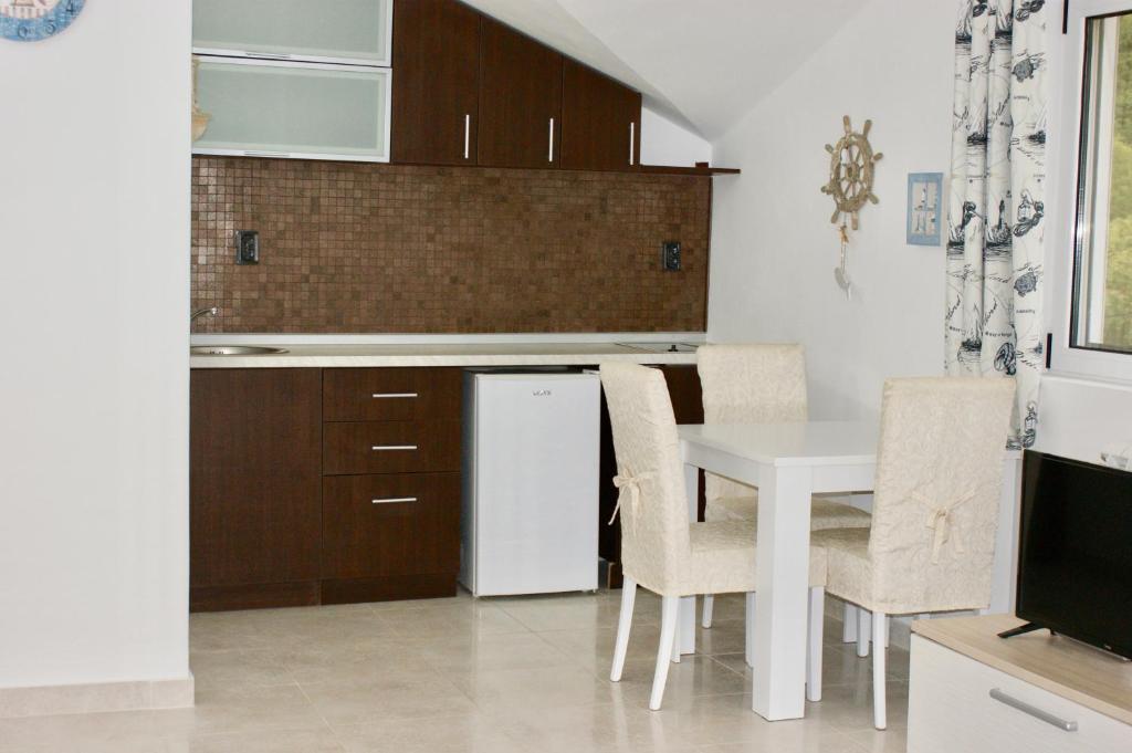 a kitchen with a white table and a white refrigerator at Studio apartments Morinj in Donji Morinj