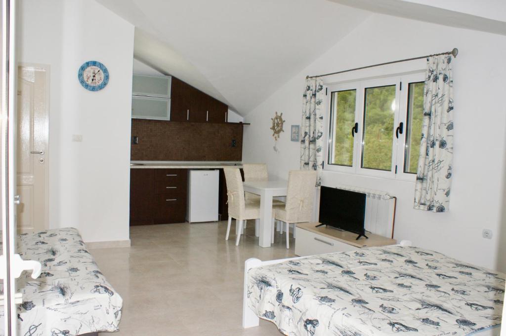 a bedroom with a bed and a kitchen with a table at Studio apartments Morinj in Donji Morinj