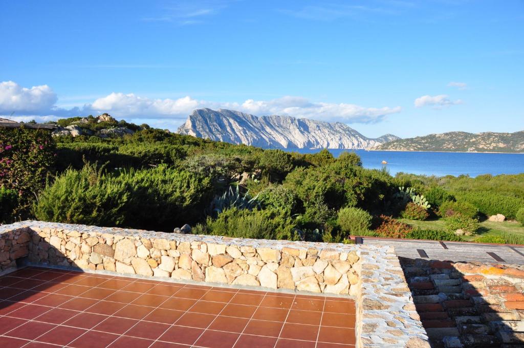 a stone wall with a view of the ocean and mountains at Case Vacanza Cala Paradiso in San Teodoro