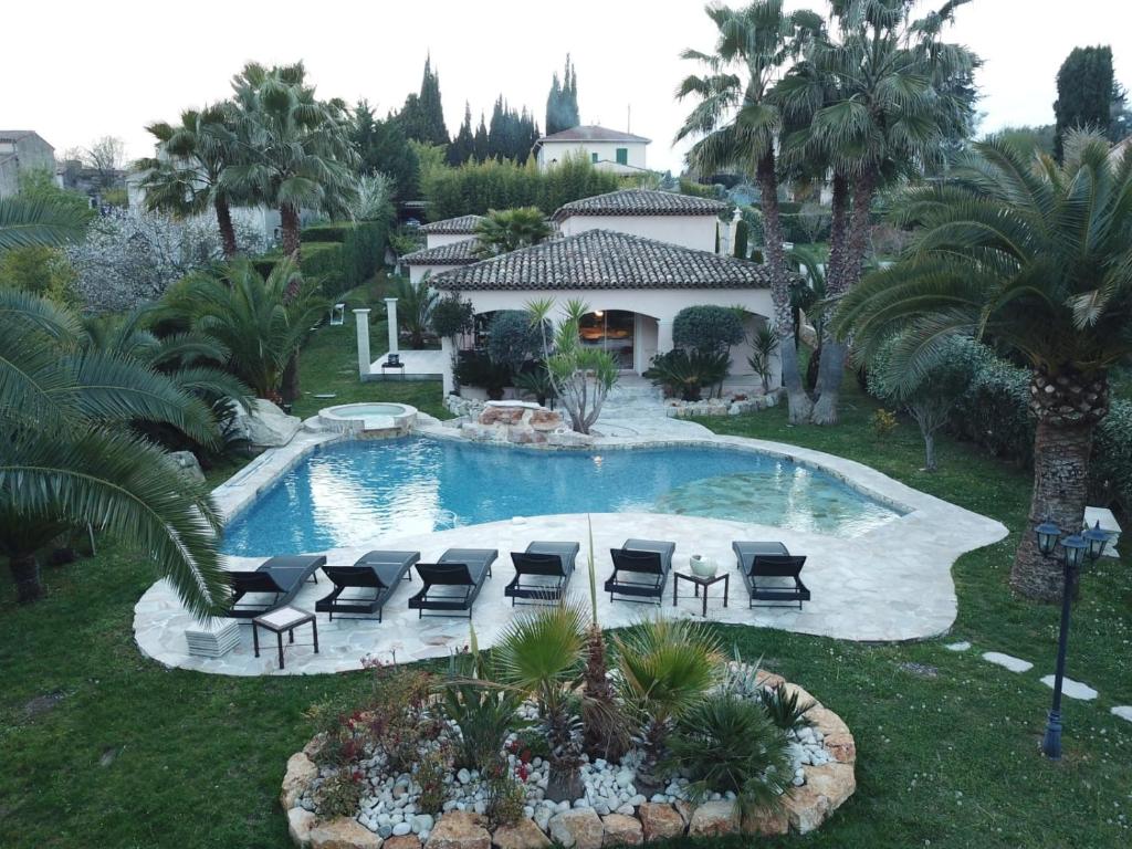 eine Luftansicht auf einen Pool mit Stühlen und ein Haus in der Unterkunft Luxueuse villa piscine et jacuzzi in Saint-Paul-de-Vence