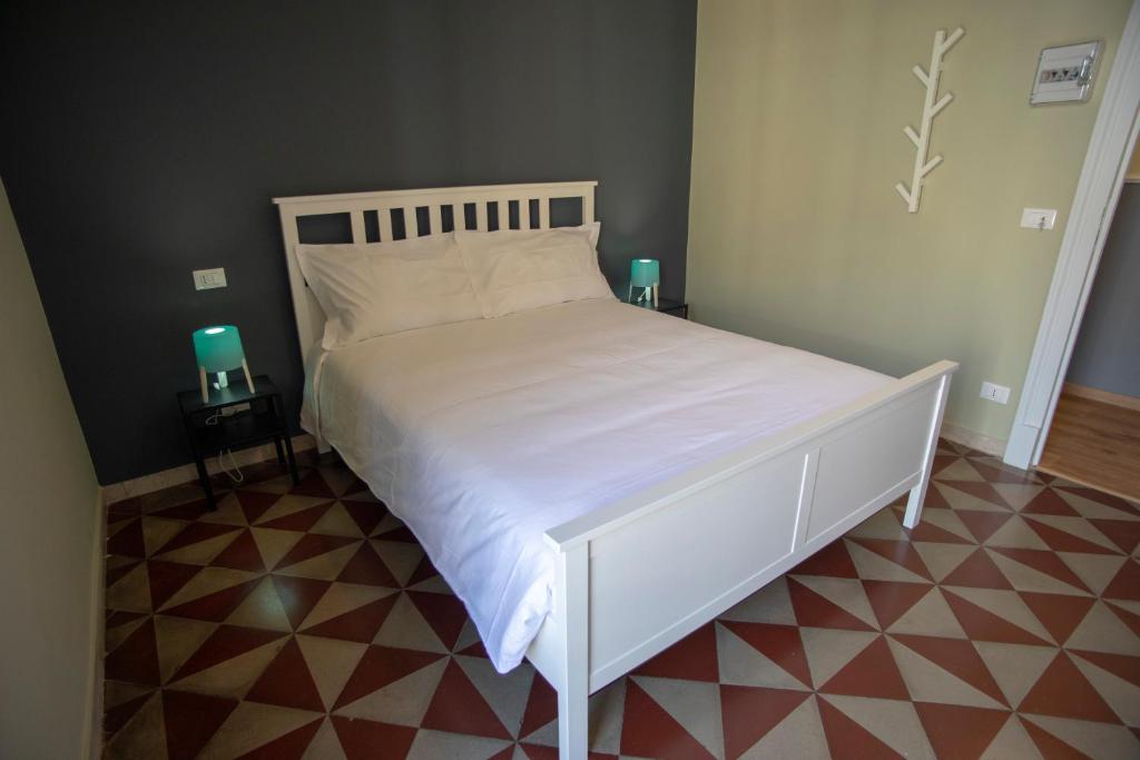 a white bed in a bedroom with two green candles at Corte dei medici - Palace in Catania