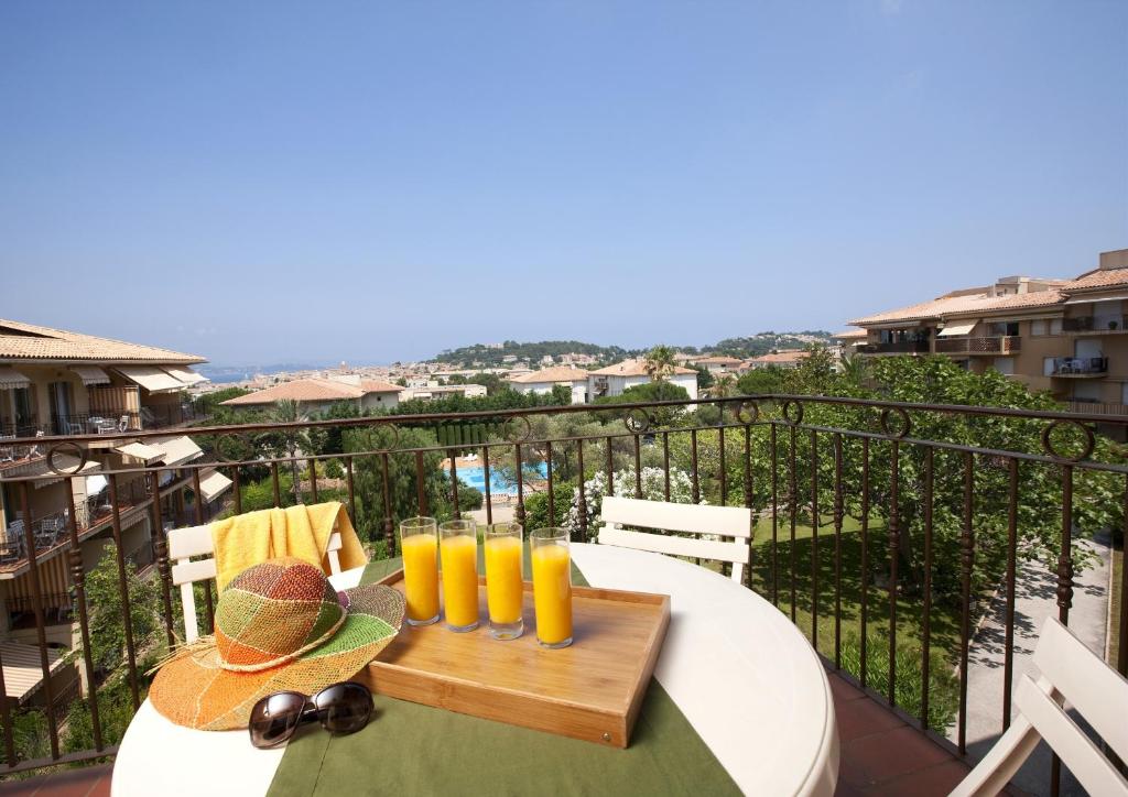 a table with glasses of orange juice on a balcony at Résidence Pierre &amp; Vacances Eden Parc in Saint-Tropez