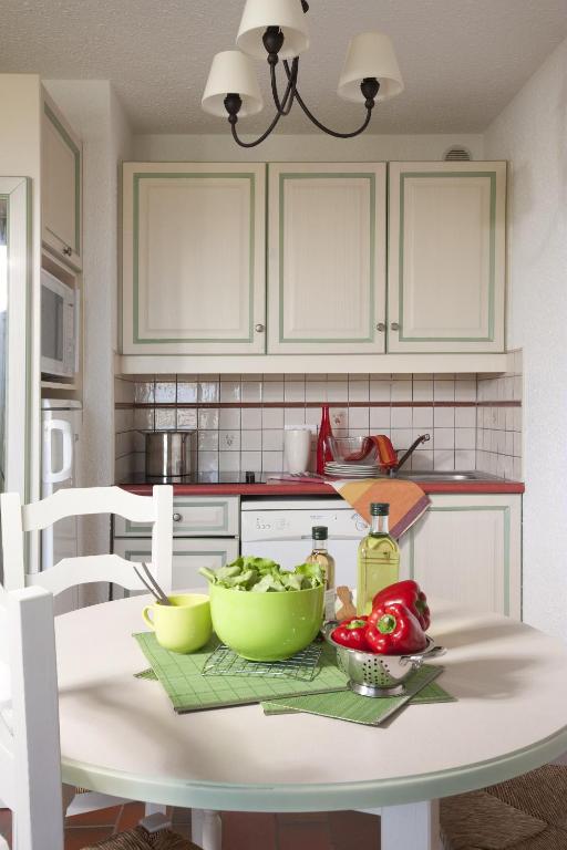 a kitchen with a table with two bowls of vegetables at Résidence Pierre &amp; Vacances Eden Parc in Saint-Tropez