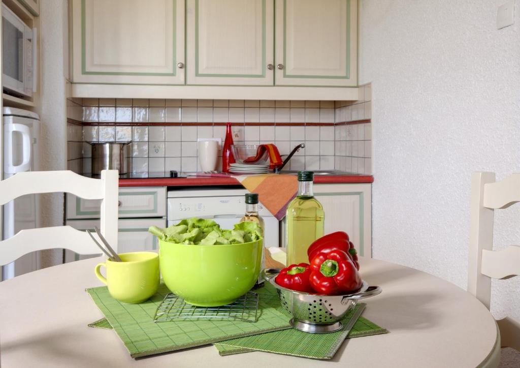 a kitchen with a table with a bowl of vegetables at Résidence Pierre &amp; Vacances Eden Parc in Saint-Tropez