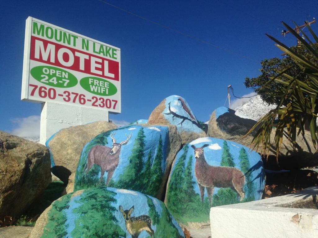 un cartel para un motel con pinturas de ciervos sobre rocas en Mount-N-Lake Motel, en Wofford Heights