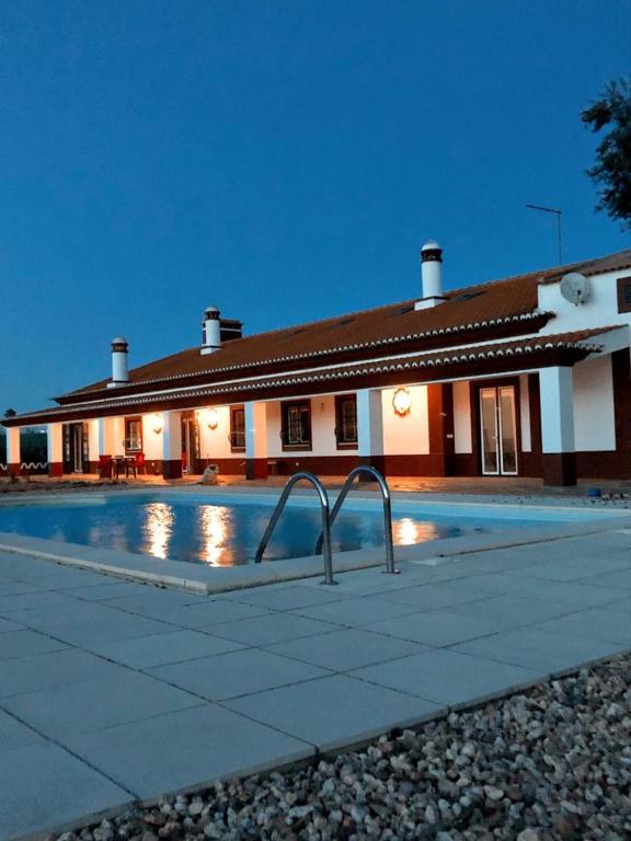 a house with a swimming pool in front of a building at Monte da Floresta B&B in Ferreira do Alentejo