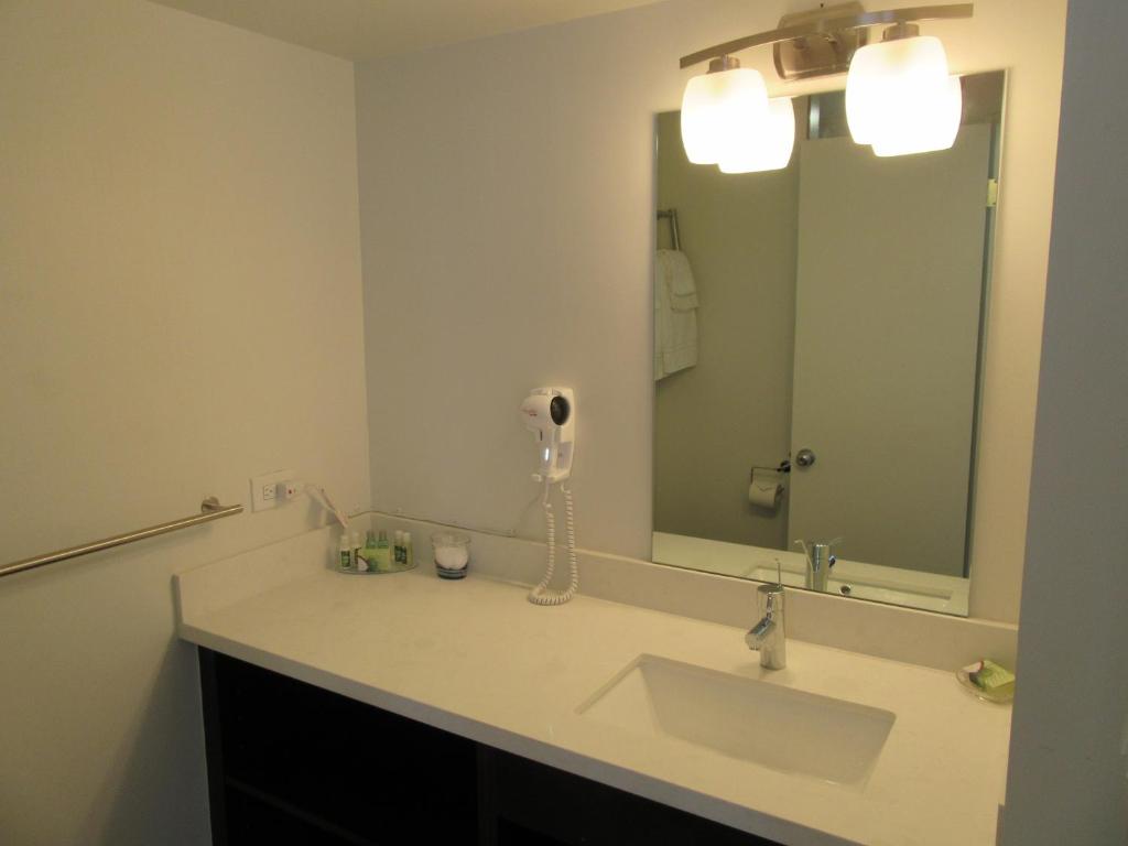 a bathroom with a sink and a large mirror at Waikiki Central Hotel - No Resort Fees in Honolulu