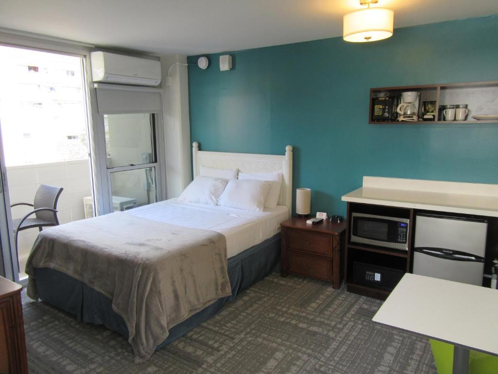 a bedroom with a bed and a blue wall at Waikiki Central Hotel - No Resort Fees in Honolulu