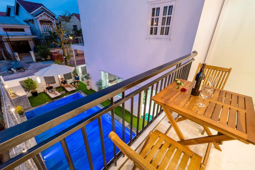a balcony with a table and a swimming pool at Horizon Homestay Hoi An in Hoi An