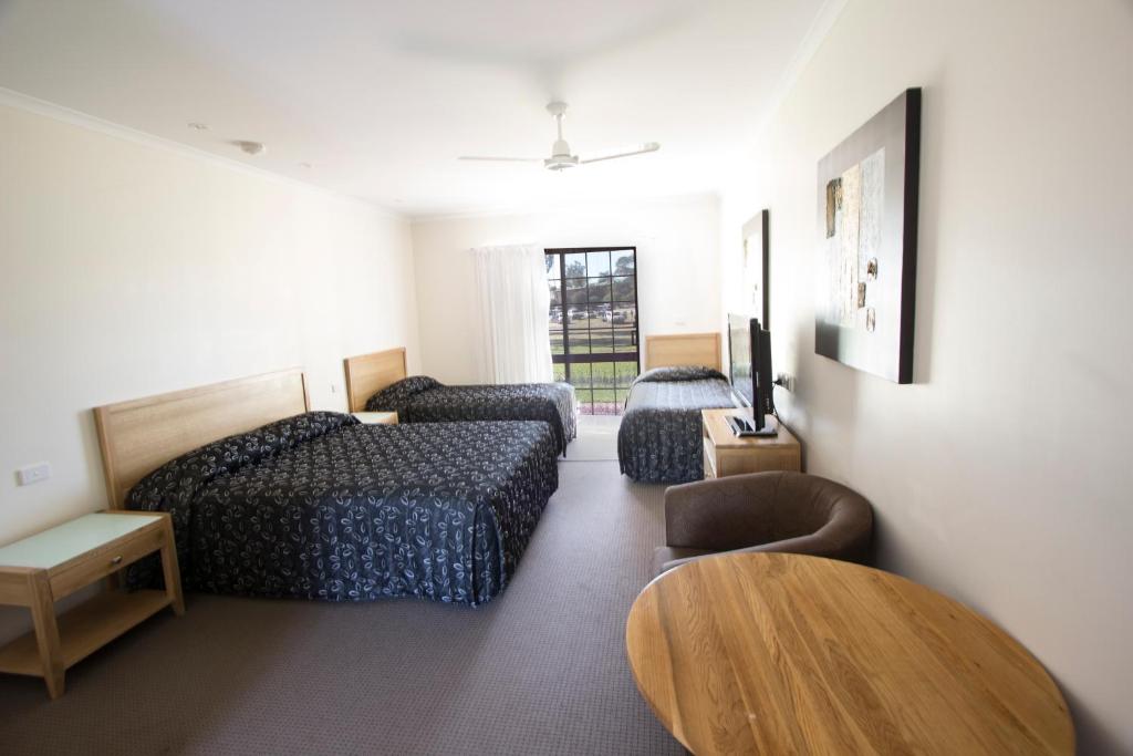 a hotel room with two beds and a table at Tocumwal Golf Resort in Tocumwal