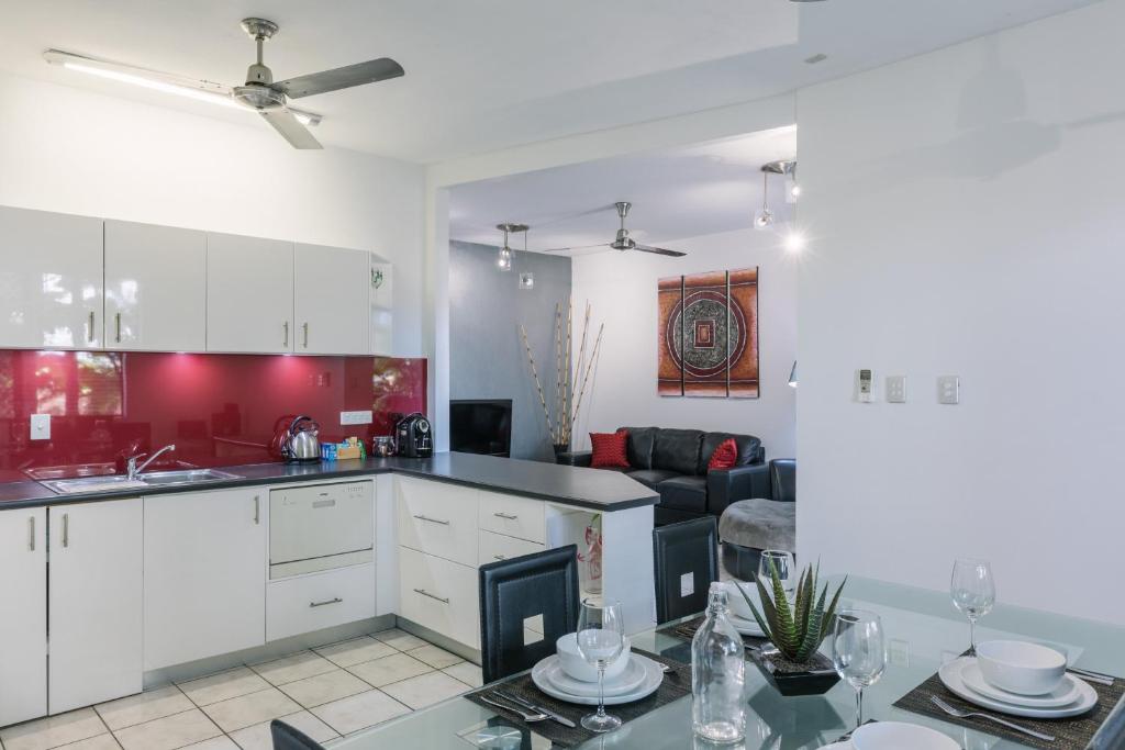 a kitchen and living room with a table and a couch at CitySide Apartment - 2 Bedroom with Private Courtyard in Darwin