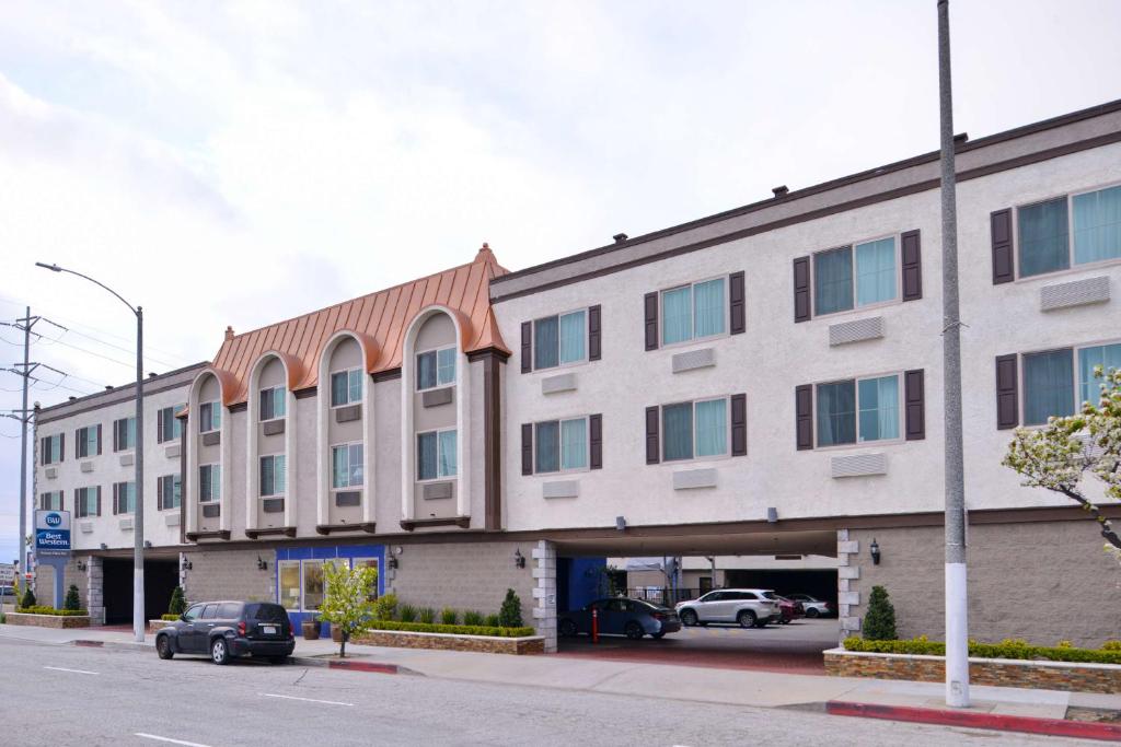 a large building with cars parked in a parking lot at Best Western Airport Plaza Inn Hotel - Los Angeles LAX in Los Angeles