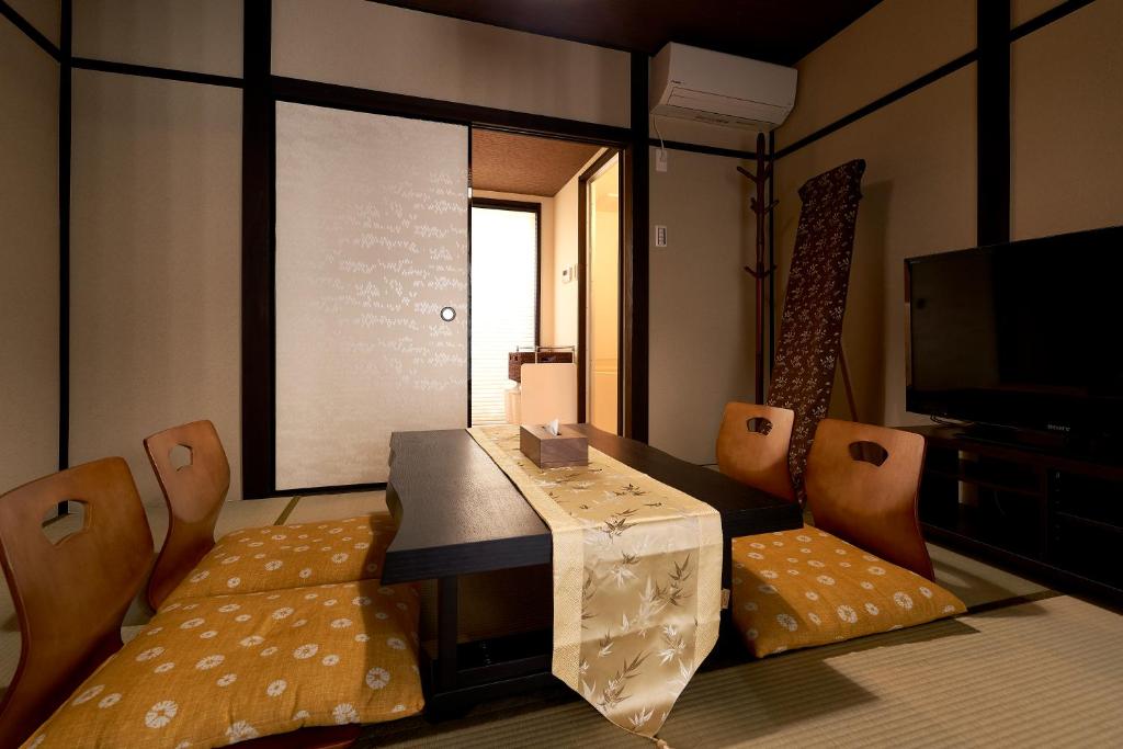 Zimmer mit einem Tisch, Stühlen und einem TV in der Unterkunft 憩 出町柳２(ikoi DemachiyanagiⅡ) in Kyoto