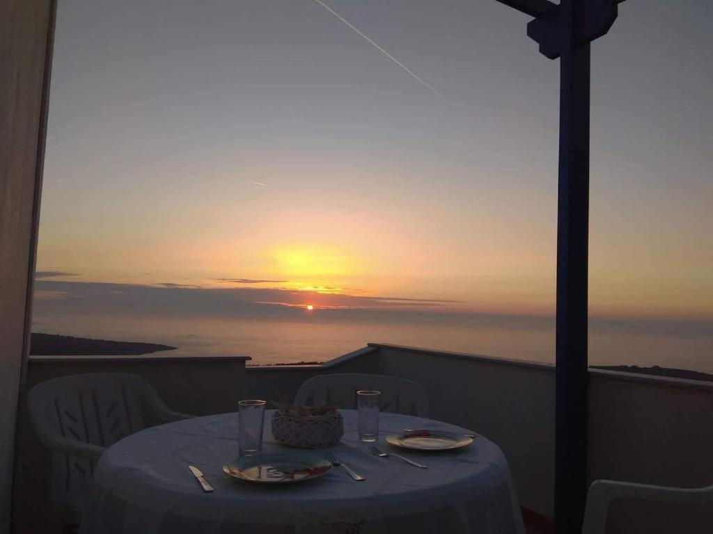 a table on a balcony with the sunset in the background at Mastiha luxury maisonette II in Líthion