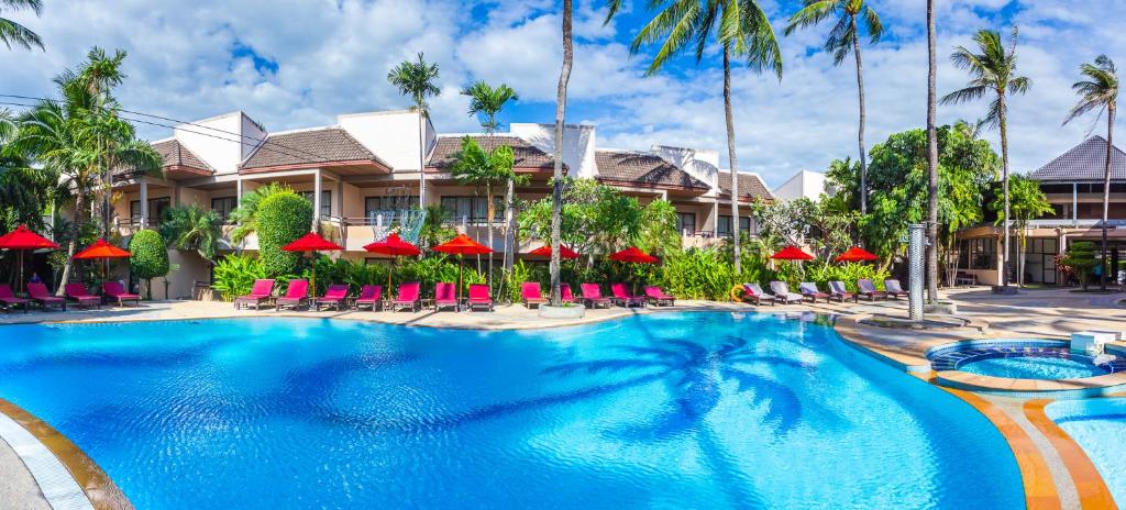 un complejo con piscina con sillas y sombrillas en Coconut Village Resort Phuket - SHA Extra Plus, en Patong Beach