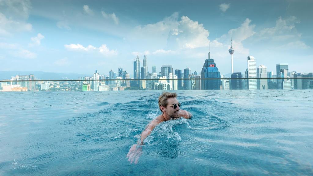 Ein Mann im Wasser in einem Pool auf einem Gebäude in der Unterkunft Penthouse on 34 - The Highest Unit and Best Views in Regalia & Private Rooftop Terrace in Kuala Lumpur