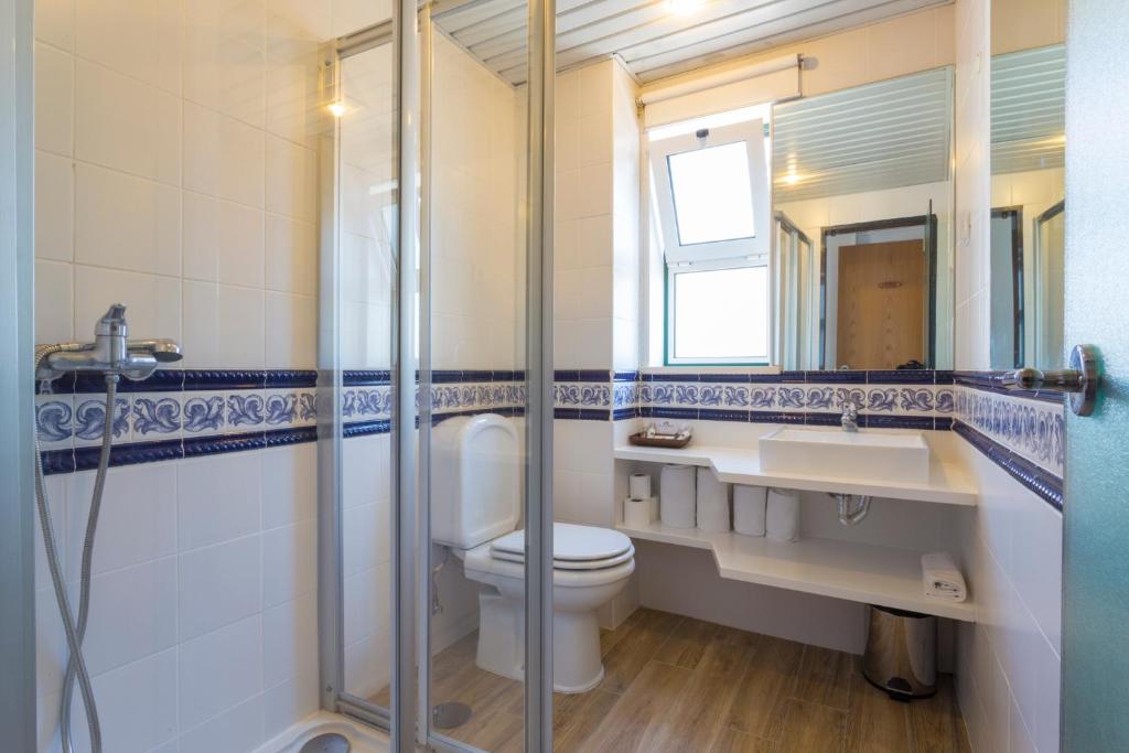 Un baño con inodoro, lavabo y espejo. en Hotel Alcatruz, en Aljezur