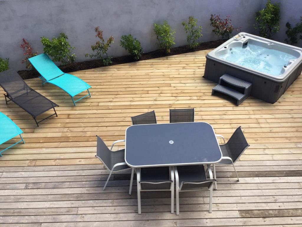 een patio met een tafel en stoelen en een hot tub bij Appartement avec jacuzzi in Porto-Vecchio