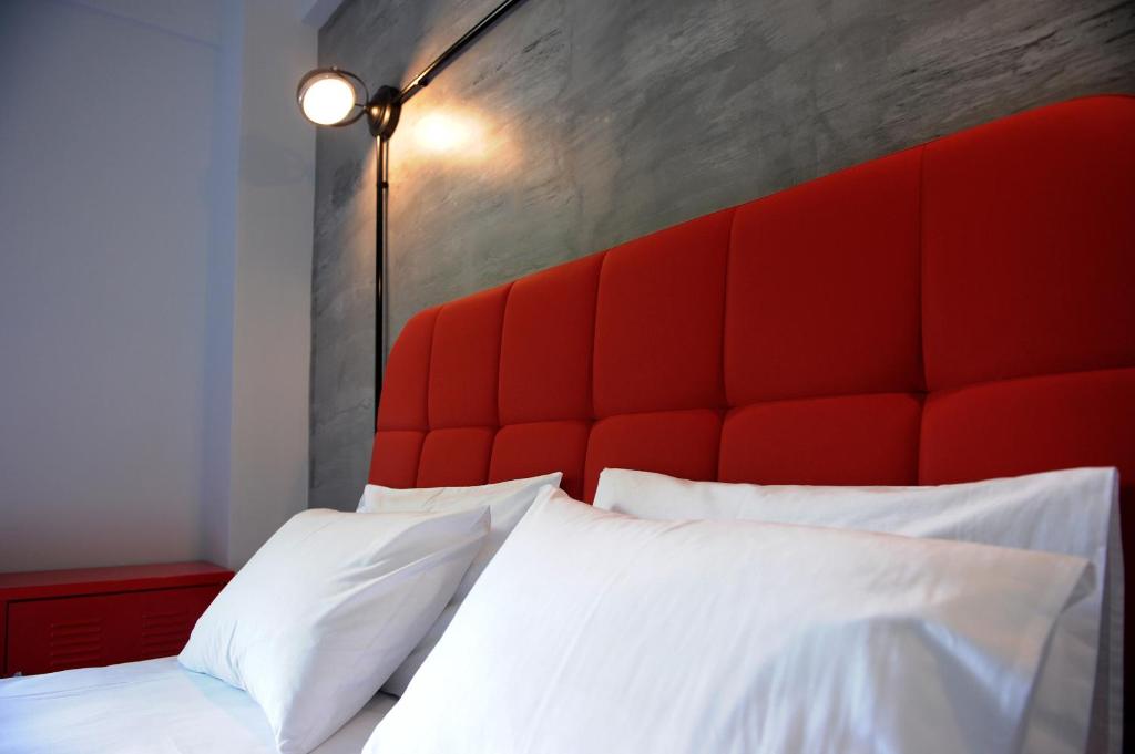 a bed with a red padded headboard and white pillows at Candy's Boutique Rooms in Asprovalta