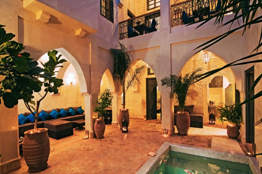 ein Gebäude mit Pool in einem Raum mit Topfpflanzen in der Unterkunft Riad Cinnamon by Marrakech Riad in Marrakesch
