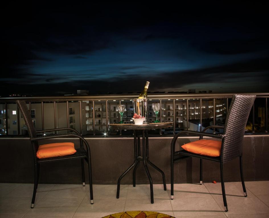 a table and chairs on a balcony at night at Manor Court Luxury Apartment in St Paul's Bay