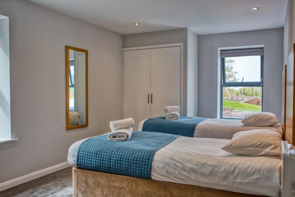 two beds in a room with a mirror and a window at Newlands Holidays in Bridport