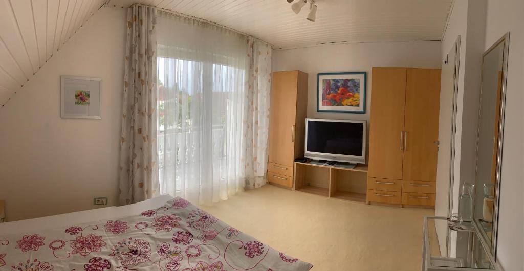 a bedroom with a bed and a tv and a window at Schöne Zimmer im Zentrum Leben in Offenburg