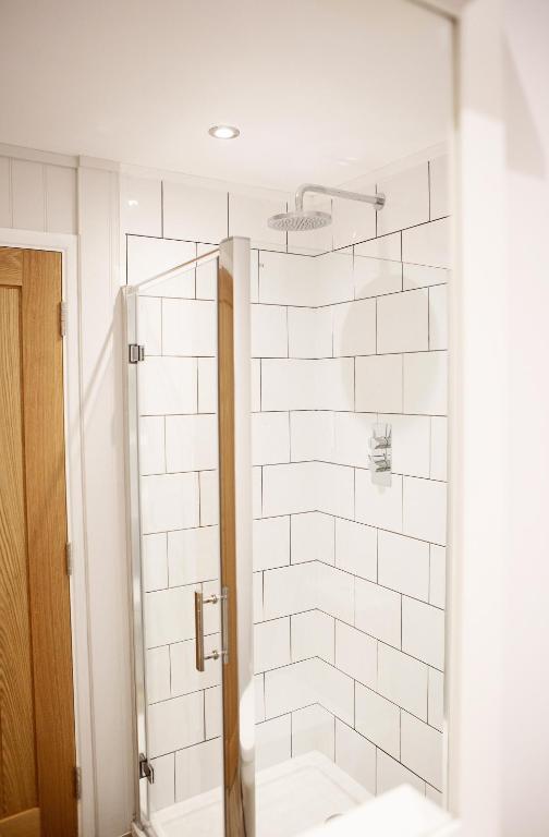 a bathroom with a shower with white tiles at Newlands Holidays in Bridport