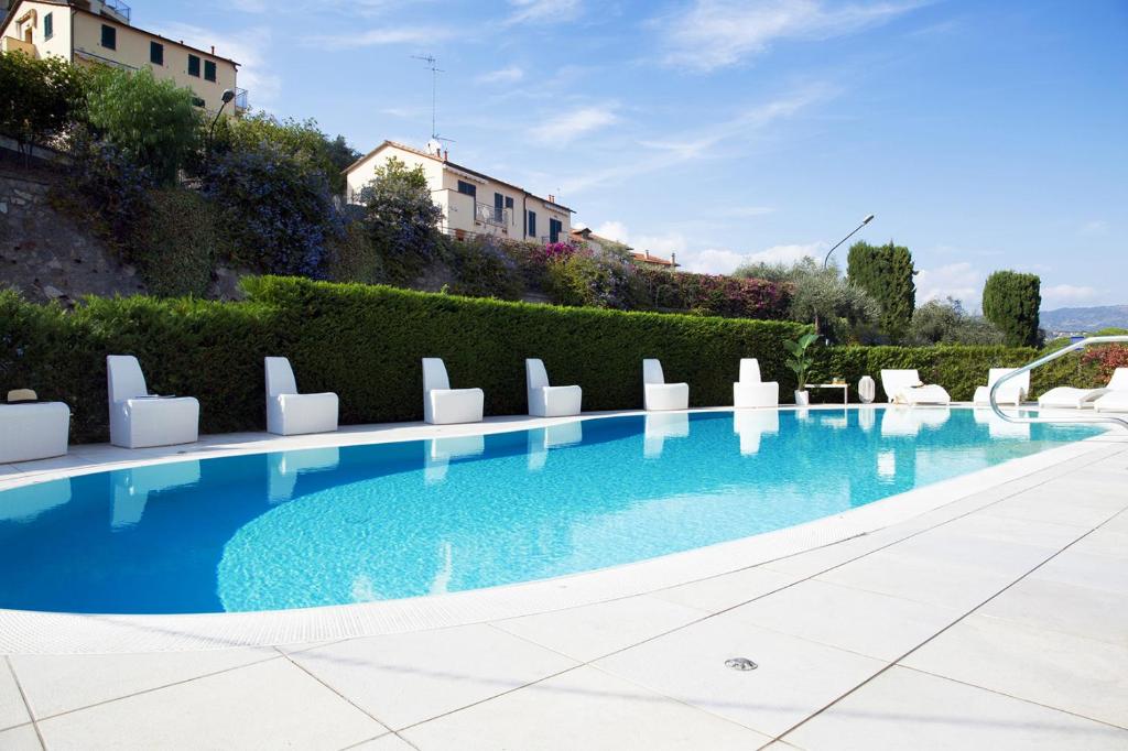 una grande piscina con sedie bianche e cespugli di Hotel Iva a Diano Marina