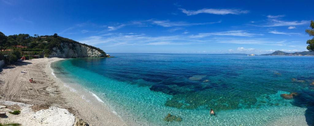a beach with people swimming in the water at Hotel Acquamarina in Portoferraio