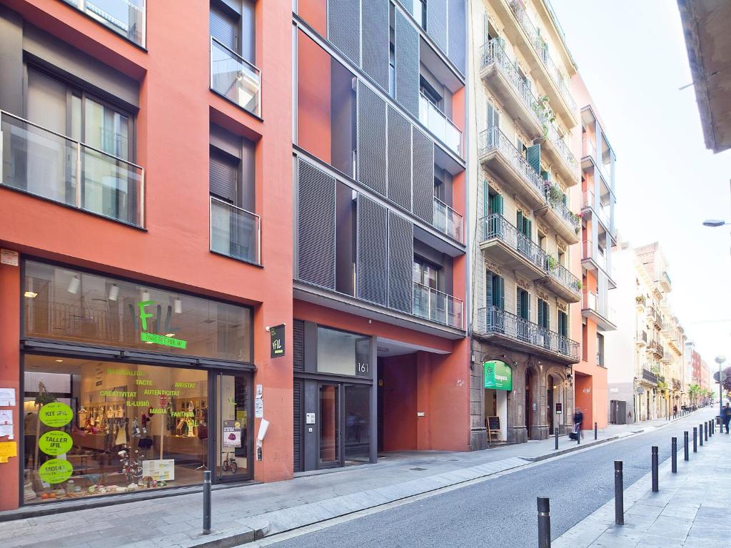 una calle urbana vacía con un edificio rojo en Bonavista Apartments - Virreina, en Barcelona