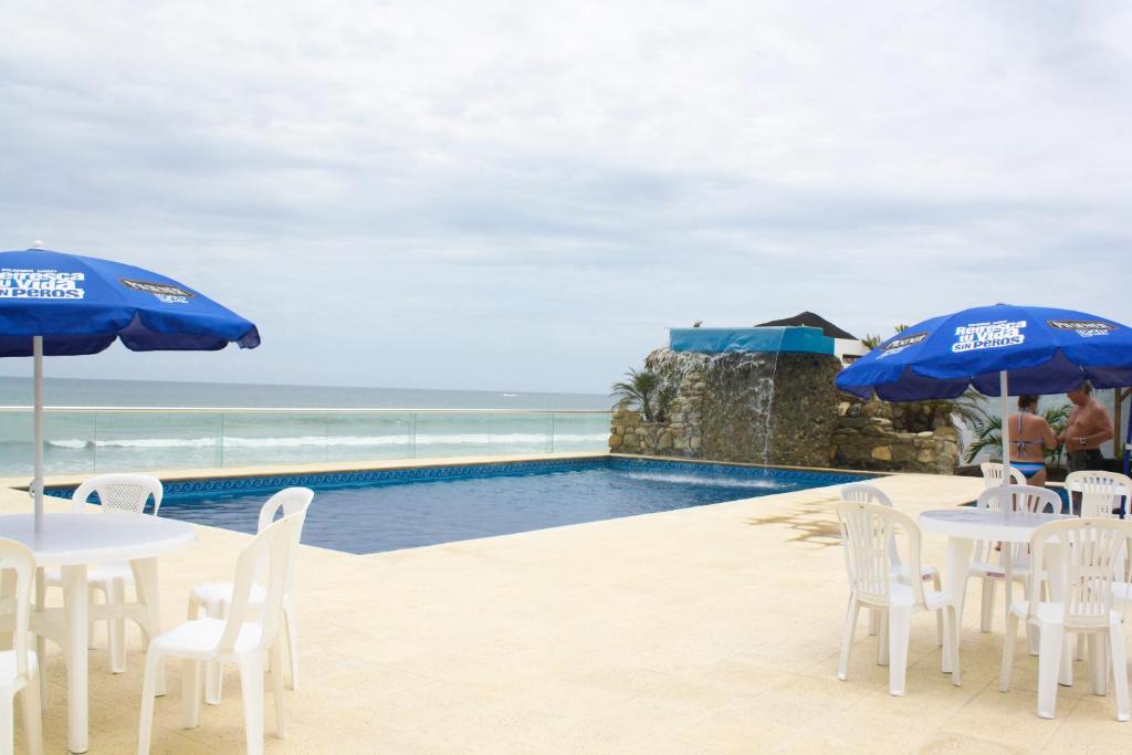a pool with tables and chairs and blue umbrellas at Casa Blanca Hotel Boutique in Santa Marianita