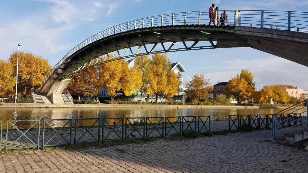 un puente sobre un río con gente caminando sobre él en Chez Daniel, un 2 pièces proche de Paris STADE de FRANCE en Aubervilliers