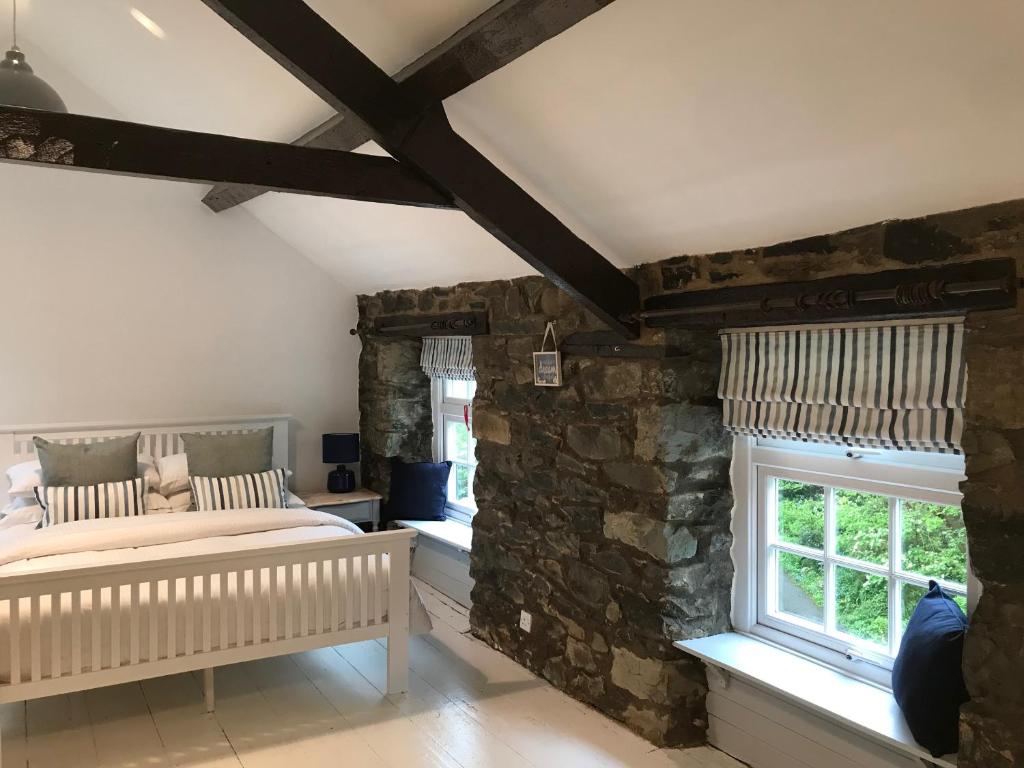 - une chambre avec un lit et un mur en pierre dans l'établissement Riverwash Cottage, à Penmaen-mawr
