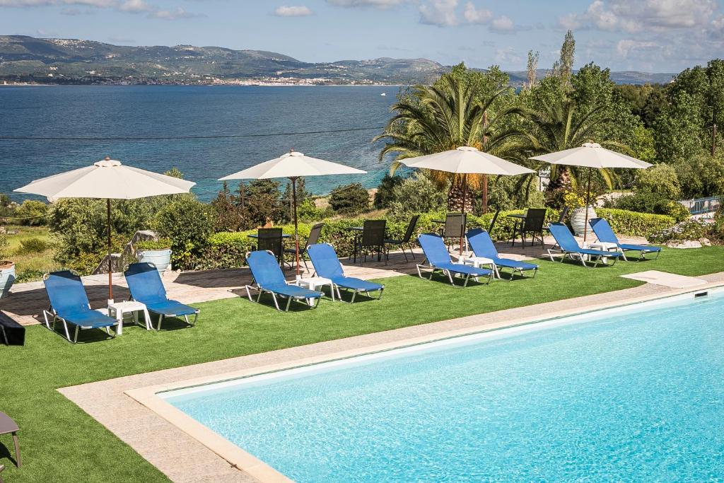 a group of chairs and umbrellas next to a swimming pool at Metaxatos Apartments in Lassi