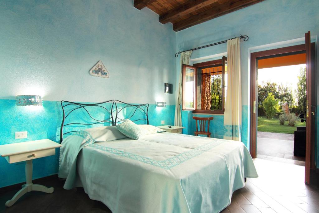 a blue bedroom with a bed and a table at SU PASSU Country House in Fertilia