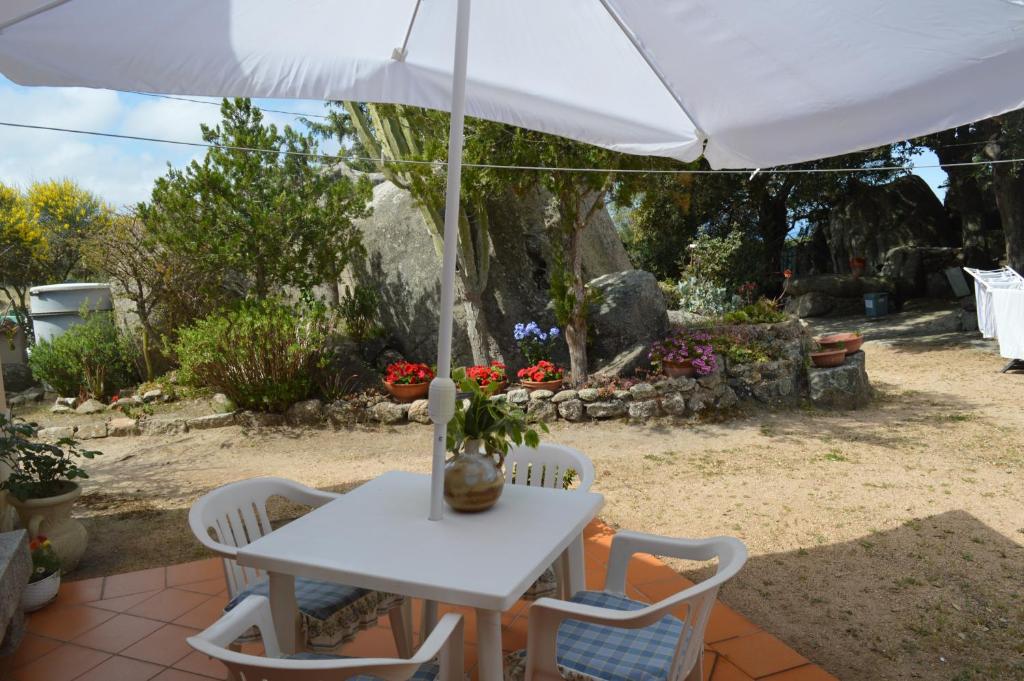 un tavolo bianco e sedie sotto un ombrellone di Casa Maltinu a Santa Teresa di Gallura