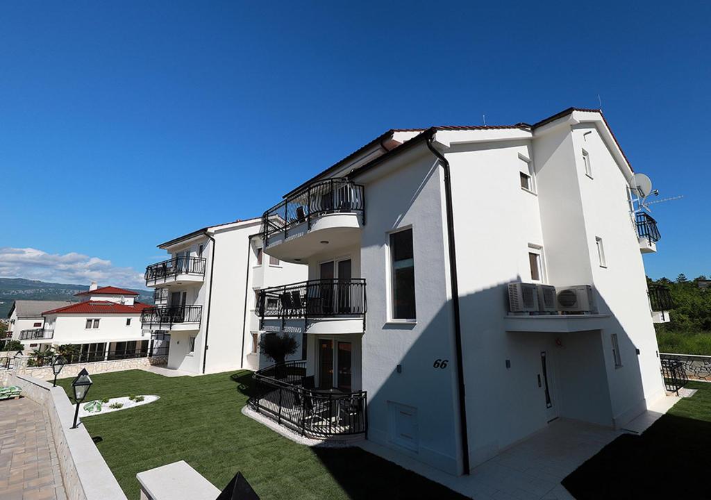 a large white building with a yard at Cool Šilo Appartement Resort in Šilo