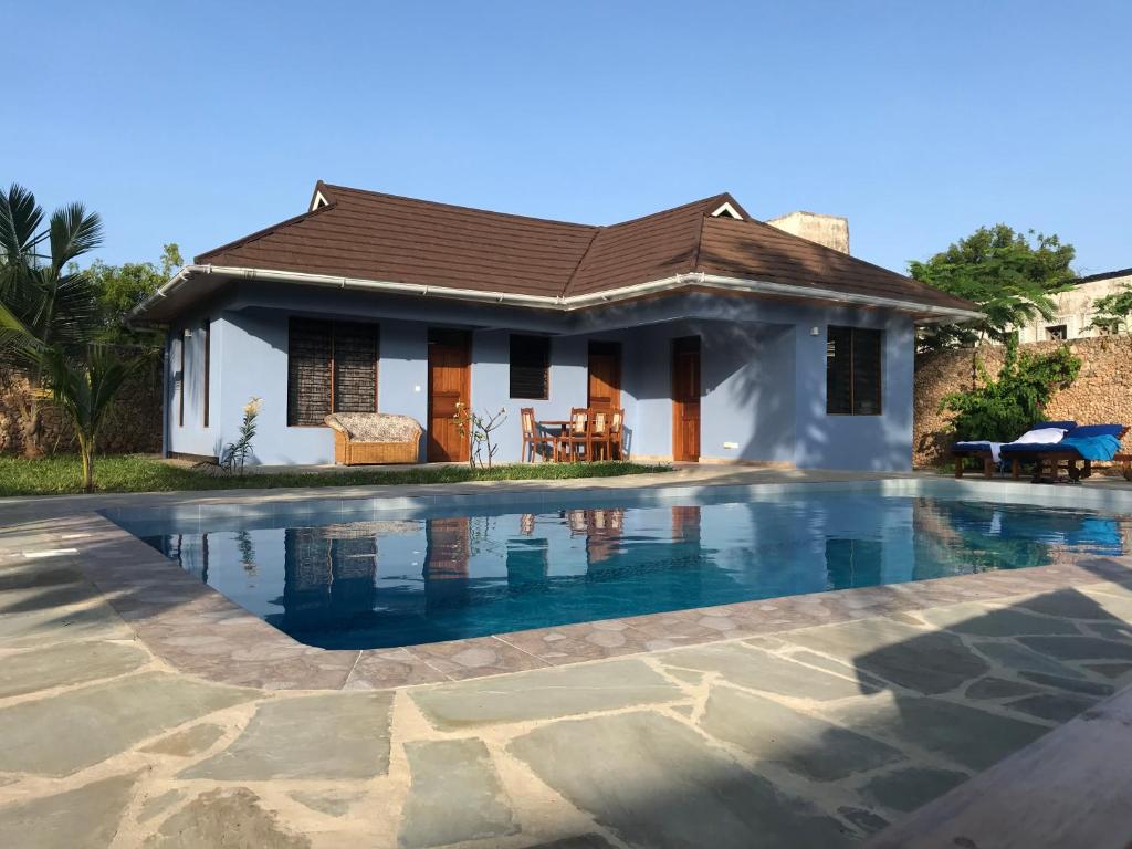 a house with a swimming pool in front of it at Lions Home in Diani Beach