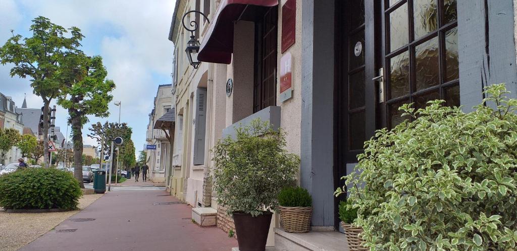 un trottoir avec des plantes en pot sur le côté du bâtiment dans l'établissement Hôtel Le Chantilly, à Deauville