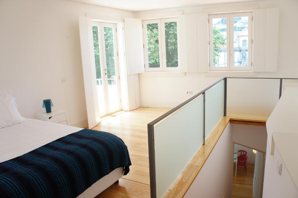 Habitación blanca con cama y escalera en Alfandega Apartments, en Oporto