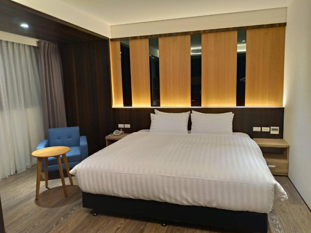 a bedroom with a large bed and a blue chair at Lantan Fanyue Inn in Chiayi City