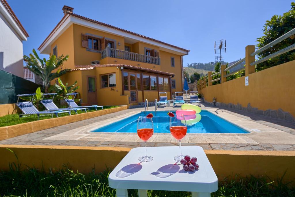 a villa with a swimming pool and two glasses of wine at Casa Mami Yaya in Firgas