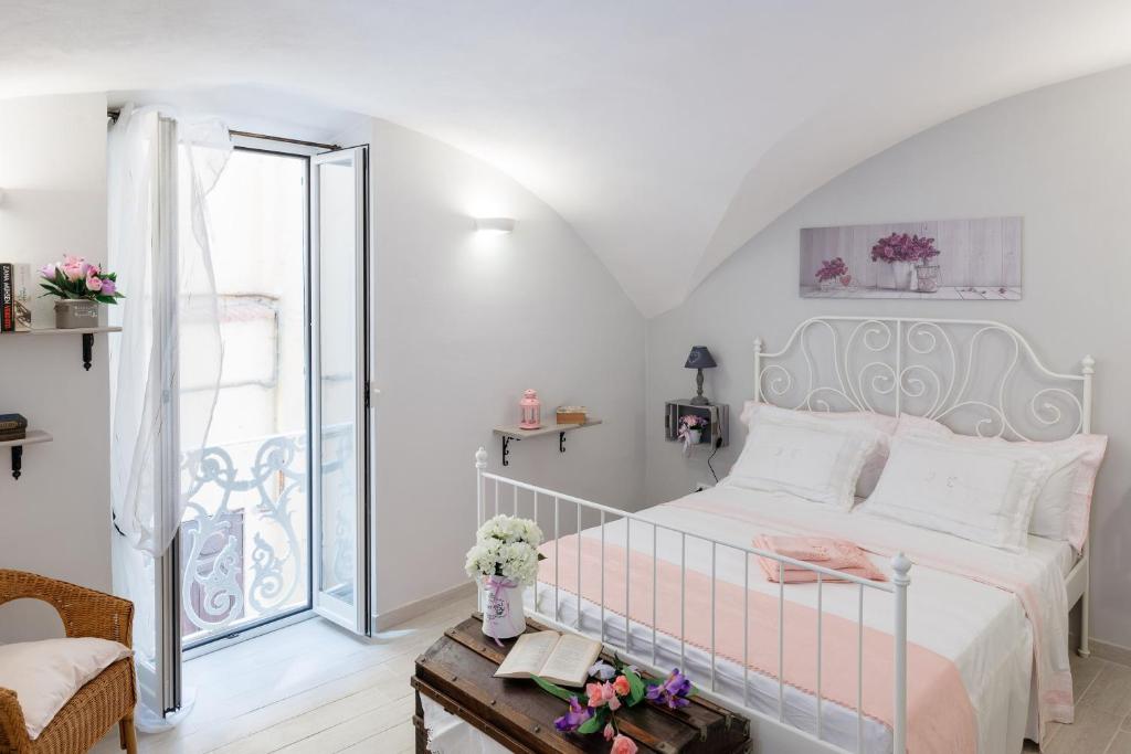 Dormitorio blanco con cama y mesa en La Casa di Anetì, en Dolceacqua