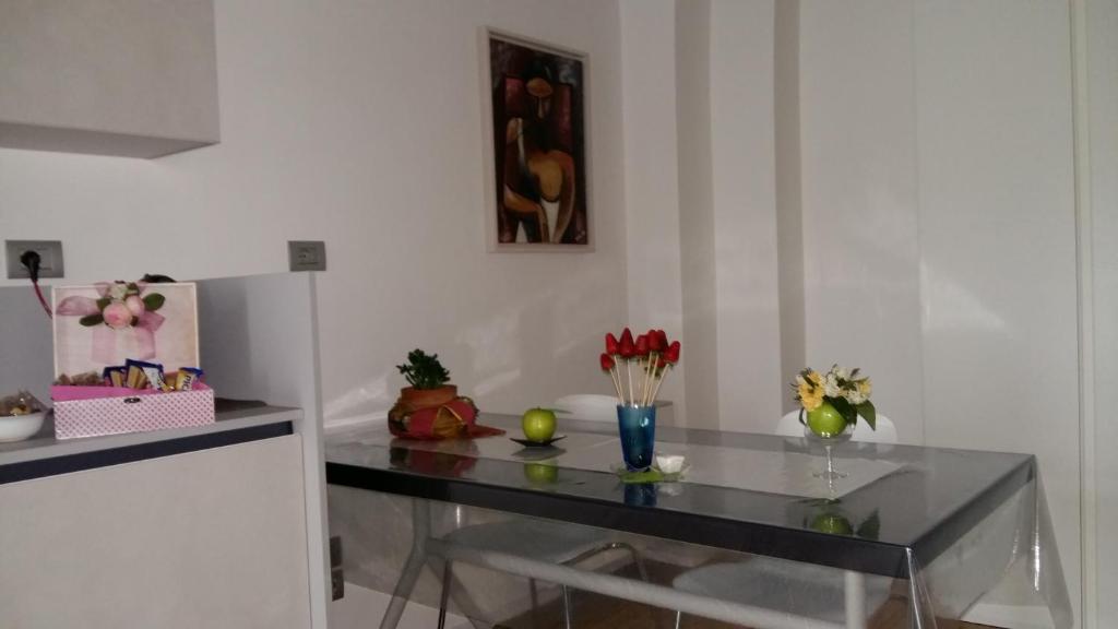 a glass table in a room with flowers and a painting at La casetta di Flavia :guest house molto accogliente in Rionero in Vulture