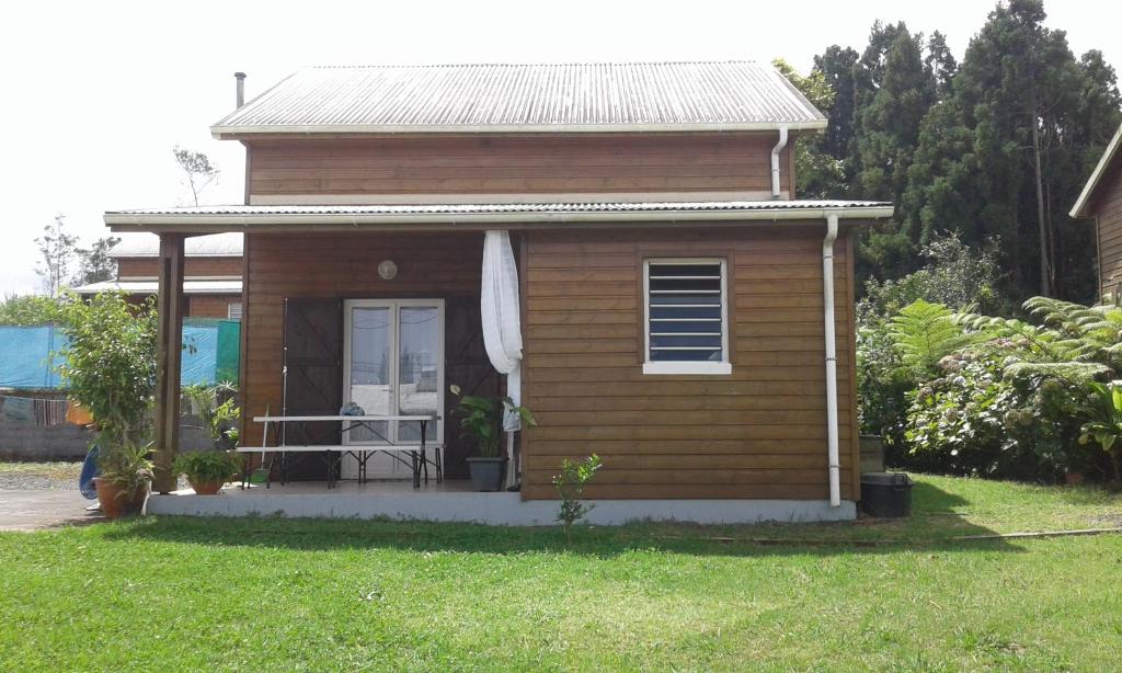 a small house with a porch and a grass yard at Kaznanou in Saint-Joseph